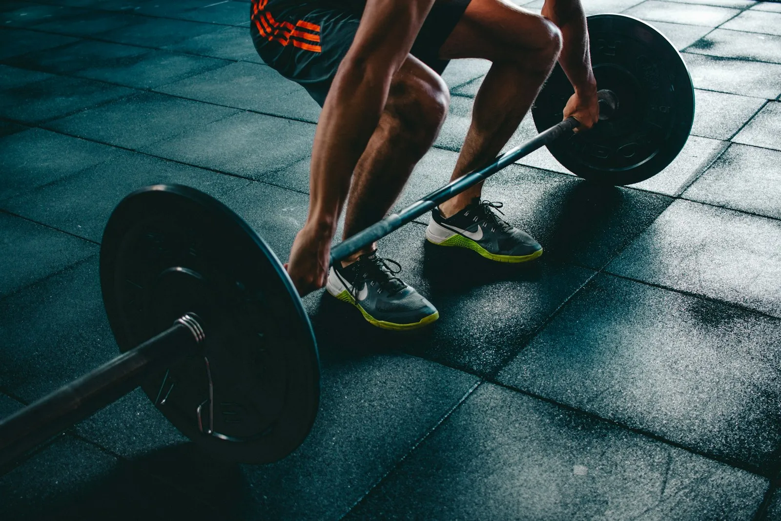 A person setting up for a heavy barbell deadlift on a dark gym floor
