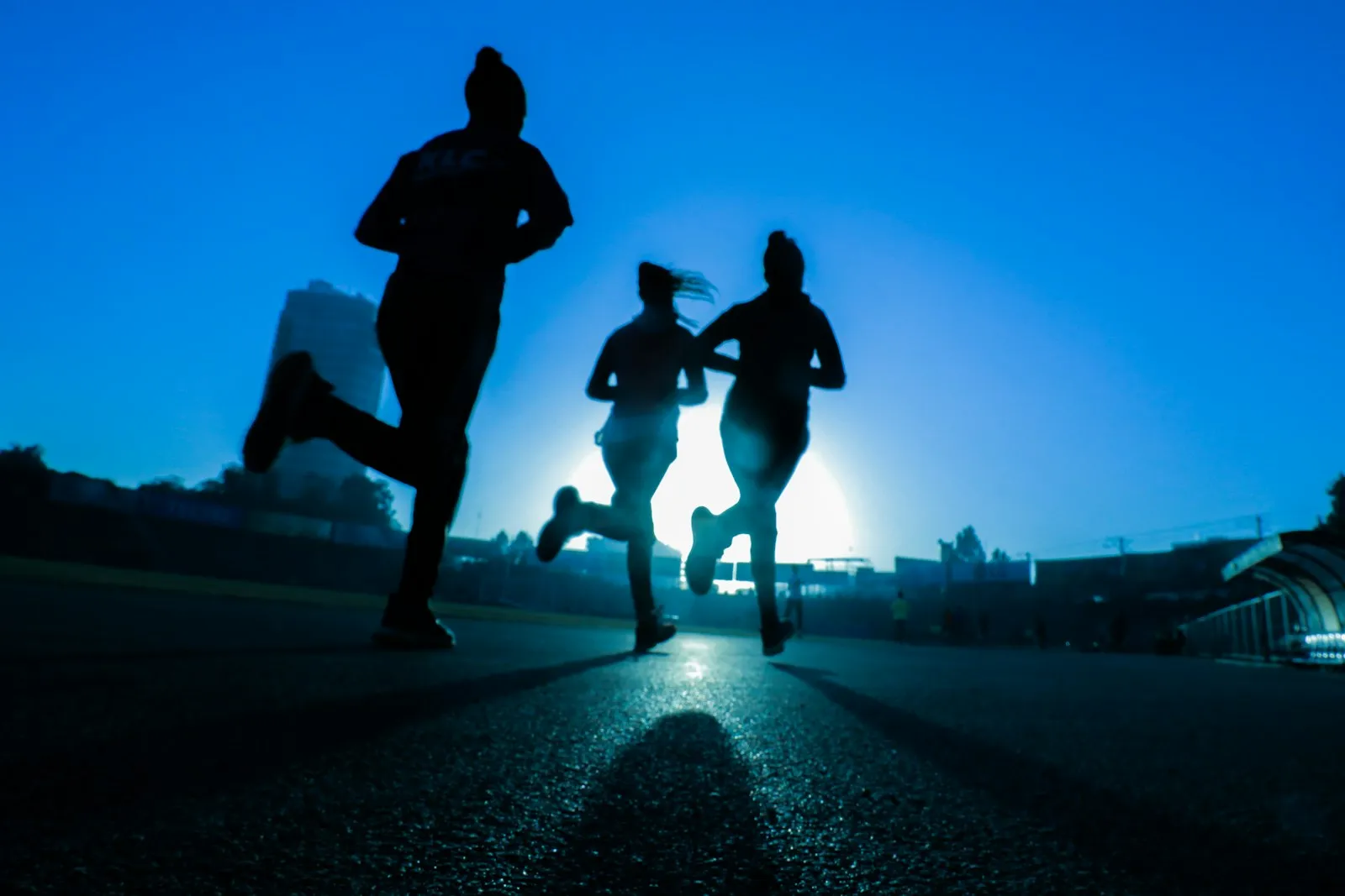 A group of people running together at dawn on an empty road