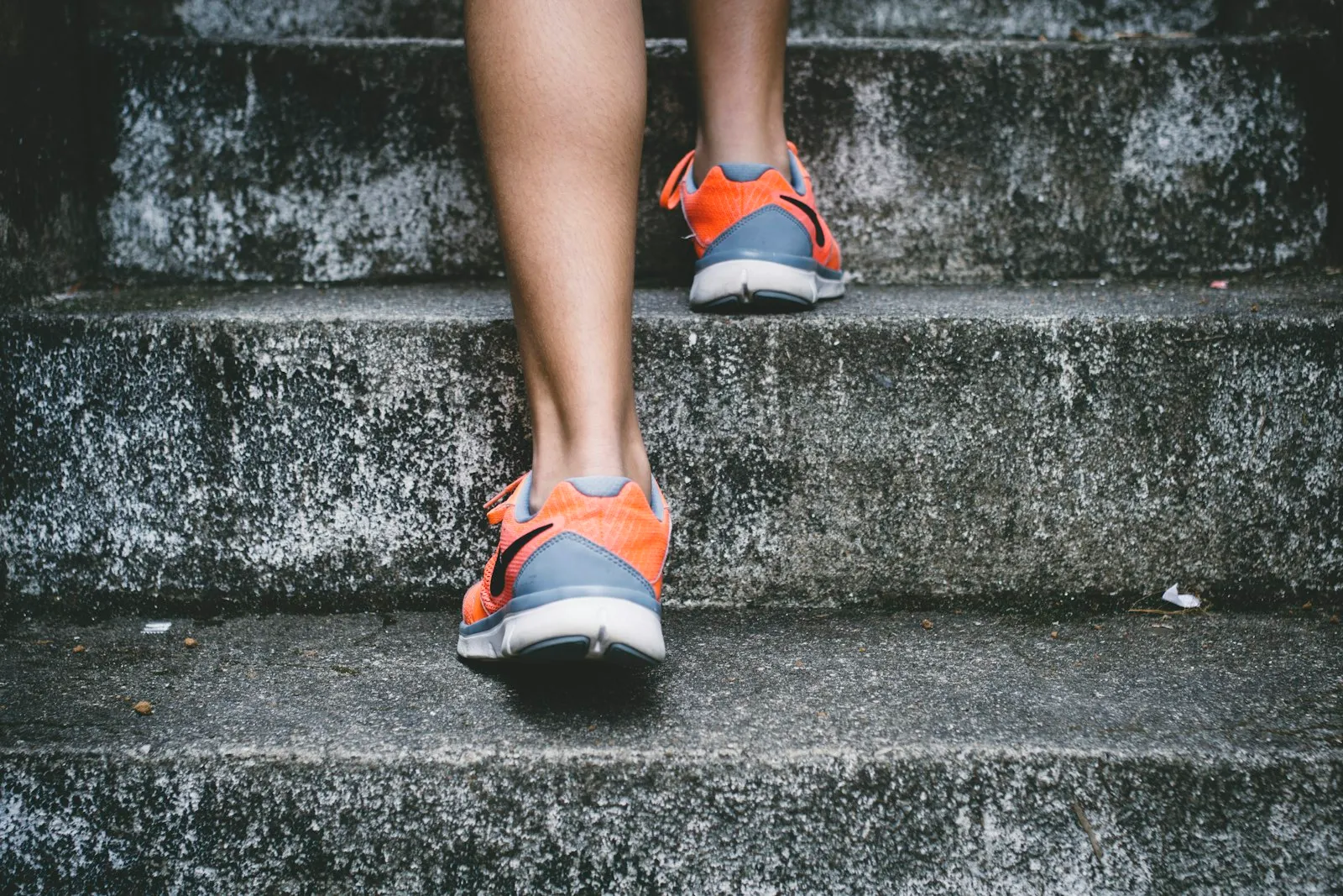 Close-up of a person climbing concrete stairs in running shoes